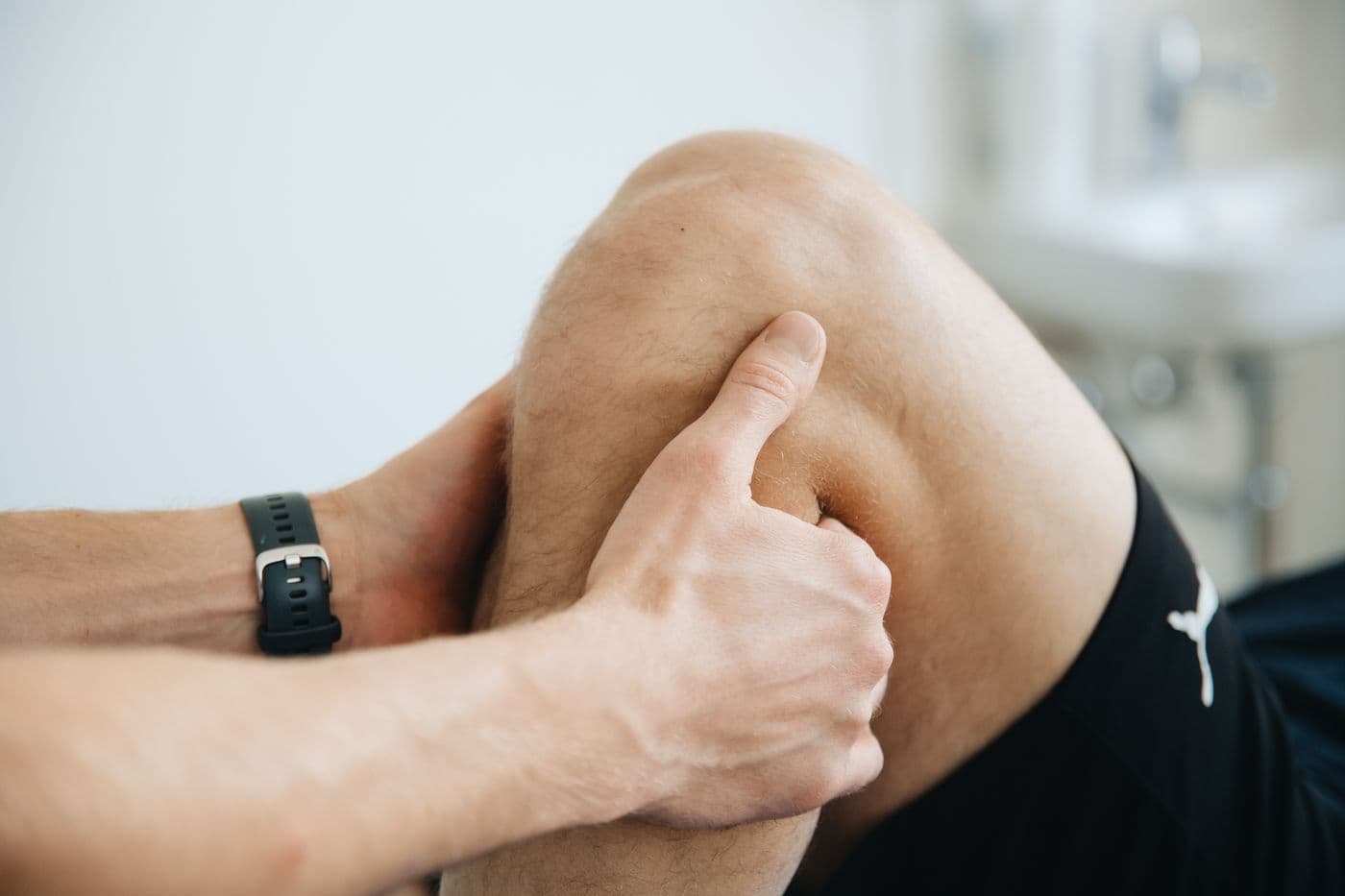 Physiotherapeutin behandelt Knie und Bein einer Patientin in einem hellen Behandlungsraum